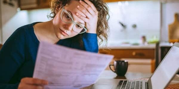 Young brunette curly female reading her bill papers, looking stressed
